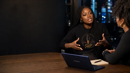 Linda Orji leading a focused creative strategy session with a client beside a navy Toshiba laptop in a New York studio